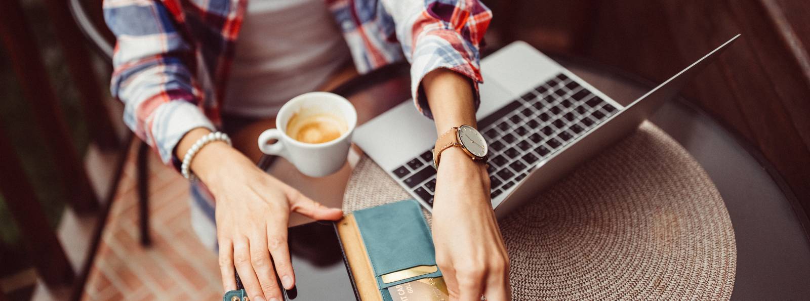 woman at a coffee shop working on her computer with her wallet out