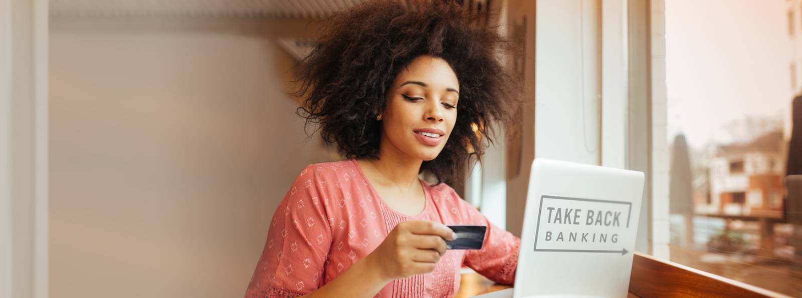 Kasasa branded photo with a woman looking at her debit card while on her computer